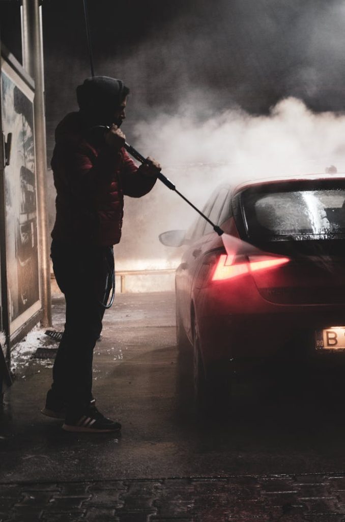 Man washing a car at night creating dramatic steam effects.
